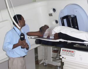 Cancer care given by a therapist who lines up the machine for the patient ready for treatment
