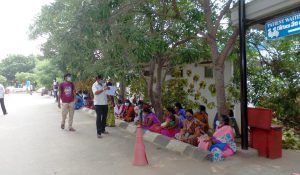 ladies sat on the path facing the road waiting for outpatient appointments at Chittoor