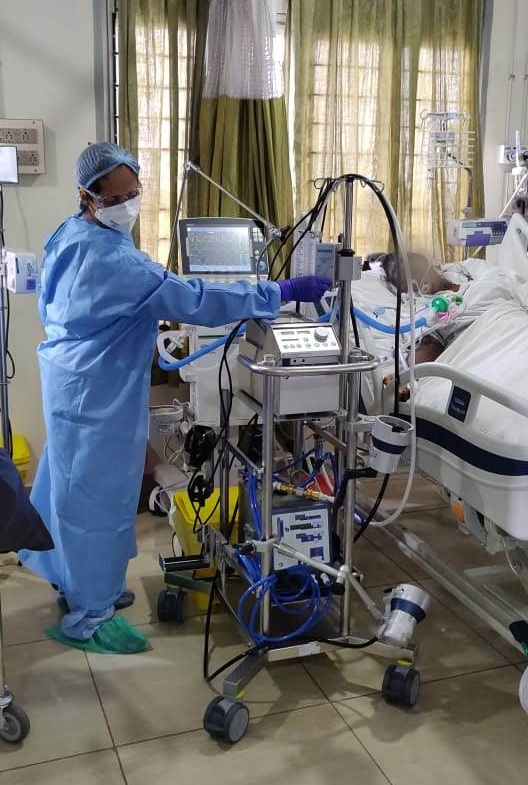 doctor in PPE attending to the equipment of patient on ventilation in ICU April 2020