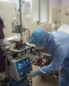 PPE equipment worn by a doctor in ICU monitoring the equipment of a patient