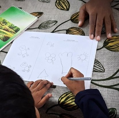 CHILD DRAWING WITH AN ADULT HAND holding the paper